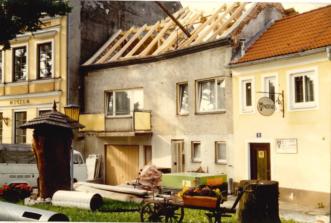 Umbau in der Schulgasse mit offenem Dachstuhl, davor ein Garten mit Holzwagen