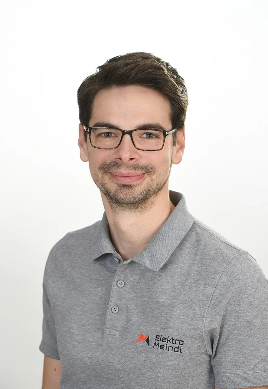 Porträt von Mag. Michael Meindl-Mayrhofer im grauen Polo mit Logo von Elektro Meindl