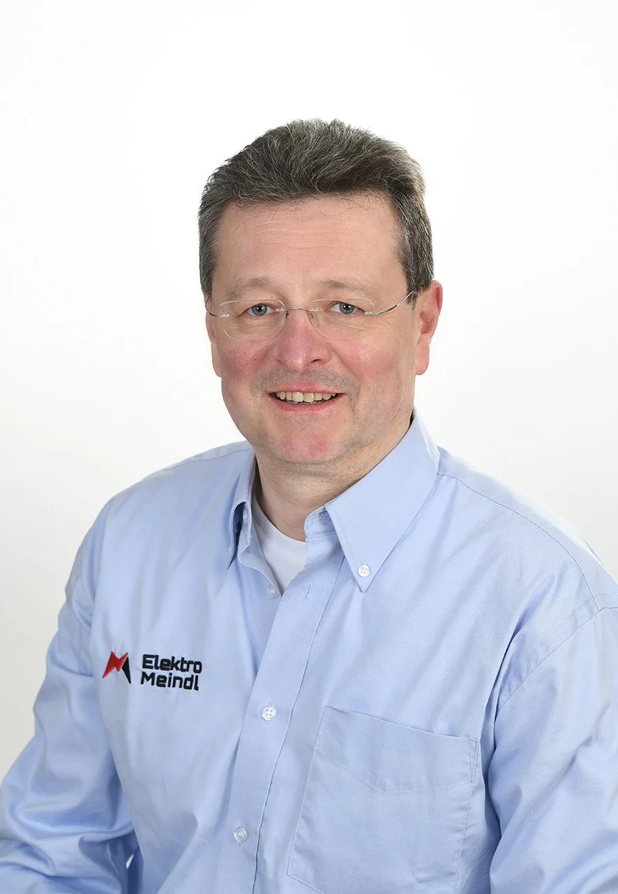 Porträt von Peter Meindl im hellblauen Hemd mit Logo von Elektro Meindl